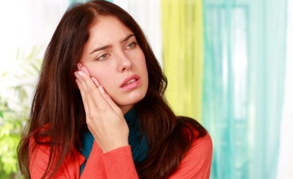 Woman holding the side of her face in pain