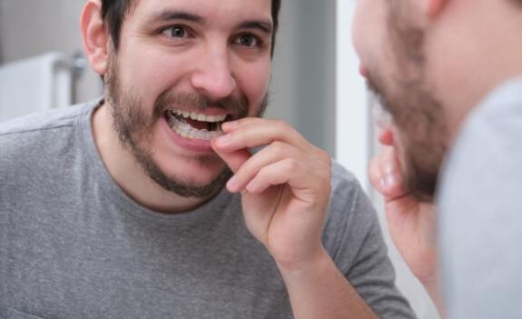 Man placing oral appliance over his lower teeth