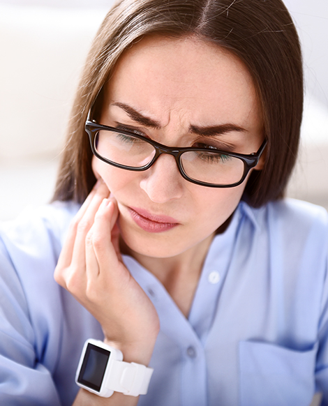 Woman in blue blouse holding her jaw in pain