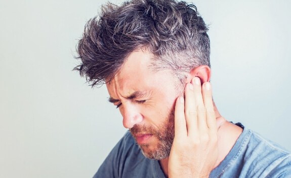 Man holding his ear and neck in pain