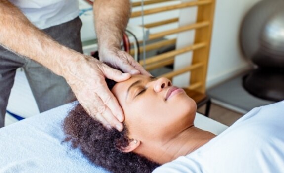 T M J team member touching head of patient for headache treatment