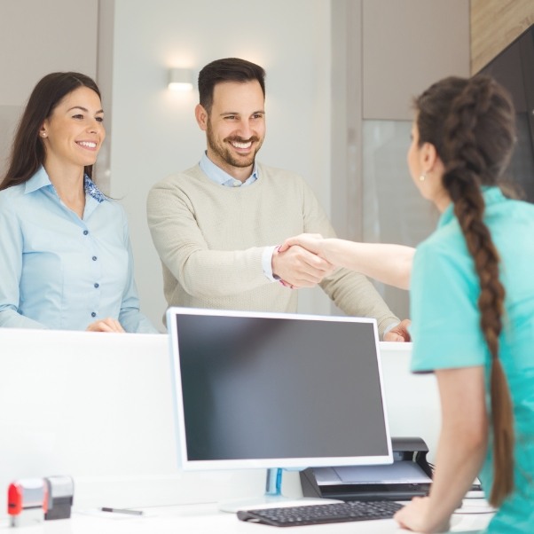 Receptionist shaking hands with a patient at front desk