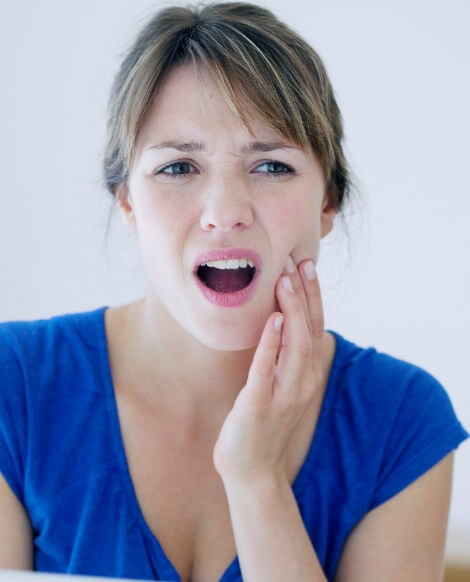 Woman in blue blouse holding her jaw in pain