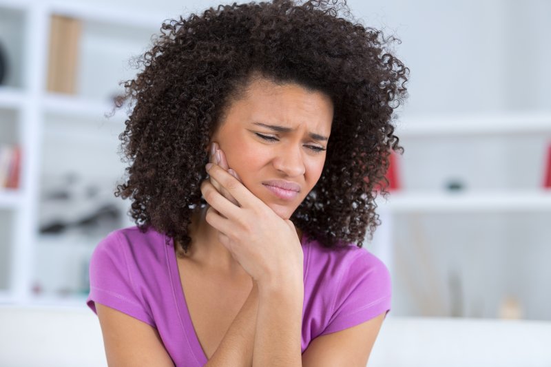 A woman holding her jaw due to painful TMJ disorder