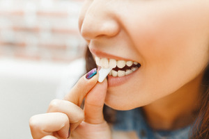 Woman biting down on a piece of chewing gum