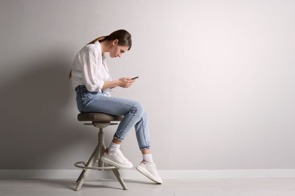 A woman with bad posture looking at her phone.