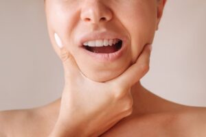 Woman holding her jaw, struggling with tightness and pain