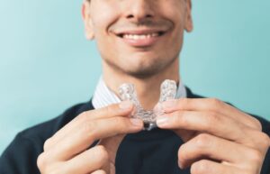 Smiling man holding oral appliance